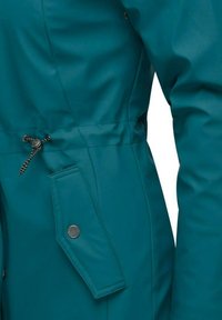 Giacca impermeabile teal con vita aderente, dotata di una tasca laterale e regolazione con cordino. Texture liscia e dettagli in metallo.