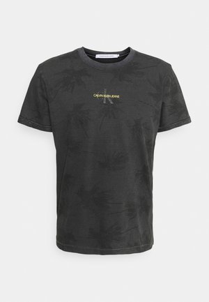 Black cotton t-shirt with a subtle palm leaf pattern, round neck, short sleeves, and yellow "CALVIN KLEIN JEANS" logo on the front.