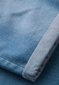 Denim-kangas, jossa on vaaleansininen sävy, taitettu reuna, sileä rakenne ja hienovarainen, klassinen kudontamalli.