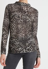 Långärmad topp i svart och beige med ett leopardmönster; har en hög halsringning och slim fit. Mjuk, texturerad tyg.