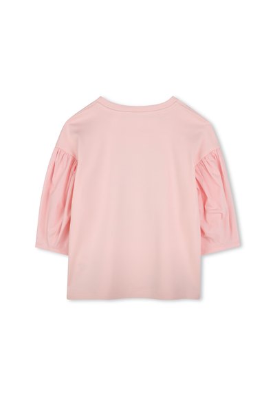 Haut rose à manches courtes avec un col rond et des manches bouffantes, fabriqué en tissu doux. Texture lisse avec des détails de couture minimaux.