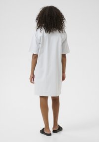 Robe chemise à manches courtes, longueur genoux, en bleu clair et blanc rayé, fabriquée dans un tissu doux avec une coupe décontractée et un design de col simple.