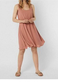 Blassrosa, ärmelloses Kleid mit lockerer Passform und gerafft Taille, aus leichtem Stoff. Kombiniert mit flachen, gewebten Sandalen.
