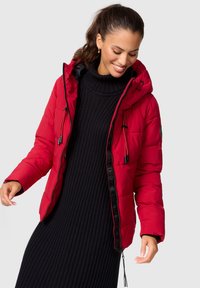 Red puffer jacket with a hood, featuring a zip front and narrow ribbed black dress. The jacket has elastic accents and visible stitching.