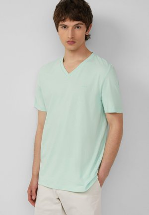 T-shirt vert menthe à manches courtes et col en V en tissu léger. Marquage discret sur la poitrine. Texture douce et coupe décontractée.