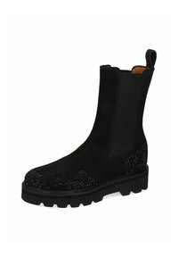 Czarny zamszowy botek za kostkę z elastycznymi panelami bocznymi, masywną podeszwą i ćwiekowanym zdobieniem wzdłuż palców i pięty. Płaska, teksturowana powierzchnia.