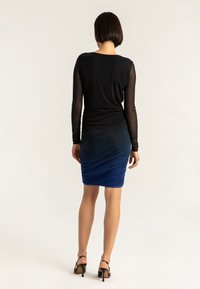 Haut noir à manches longues en tissu transparent et jupe crayon bleue à effet dégradé ombré froncée, avec une texture lisse et une longueur au-dessus du genou.