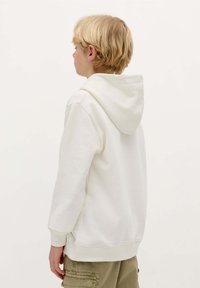 Witte katoenen hoodie met een trekkoordcapuchon, lange mouwen en ribgebreide manchetten. De stof lijkt zacht en lichtjes gestructureerd.