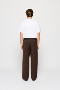 Brune vide bukser med bælte i taljen og to baglommer, parret med en simpel hvid t-shirt med korte ærmer. Glat stoftekstur.