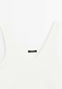 Witte geribbelde tanktop met brede bandjes en een ronde halslijn, voorzien van een klein zwart label aan de achterkant.