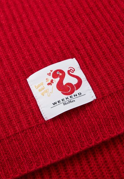 Tejido de punto acanalado rojo con una etiqueta blanca que presenta un diseño de serpiente roja juguetona, corazones y el texto “WEEKEND MaxMara.”