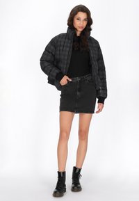 Černá nadýchaná bunda s kostkovaným vzorem, kombinovaná s černou džínovou sukní a černými šněrovacími botami. Hladká textura, zkrácený design.