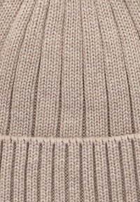 Jasnobeżowa, dziana czapka beanie z prążkowanym wzorem, posiadająca pionowe paski oraz grubą opaskę na dole dla dodatkowego ciepła.