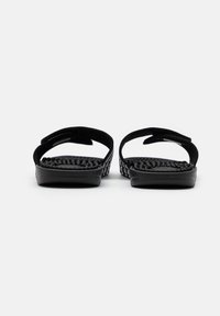 Mustat flip-flopit, joissa on teksturoitu pohja ja kaksi leveää hihnaa, valmistettu pehmeästä materiaalista. Pohjat ovat sileät ja niissä on lievä kaarevuus.