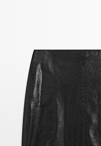 Jupe en maille noire avec un tissu texturé et transparent, ornée de rayures verticales et d'une taille lisse. Silhouette simple et ajustée.