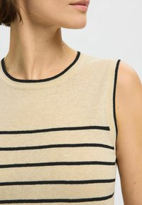 Beige sleeveless top with black horizontal stripes, round neckline, and black trim. Fabric appears smooth and lightweight.