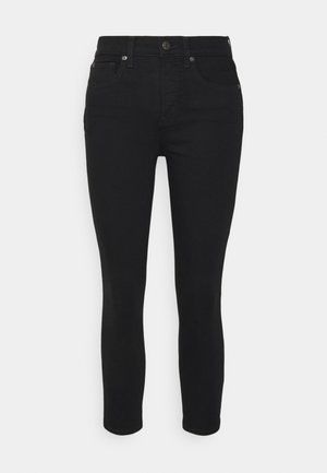 Black denim skinny jeans with a mid-rise waist, five pockets, and a zip fly. Features subtle stitching and metal hardware accents.