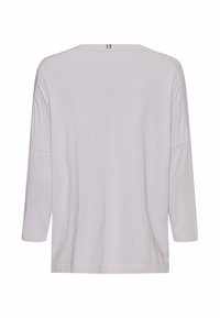 Lichtgrijze lange mouwen top met een ontspannen pasvorm, zachte textuur, wijde halslijn, en een kleine verticale accent aan de achterkant.
