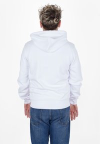 Felpa bianca con cappuccio, dal tessuto morbido, con polsini a coste e tasca a marsupio, abbinata a jeans in denim blu con tasche posteriori.
