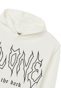 Witte hoodie met een groot zwart grafisch tekstontwerp met scherpe, hoekige letters. De stof lijkt zacht met een gestructureerde afwerking.