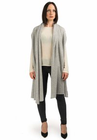 Lys grå sjal lavet af blødt stof, lagt over en cremefarvet sweater og sorte jeans. Stiletthæle fuldender outfittet.