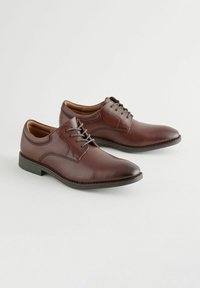 Chaussures en cuir marron à lacets, avec des orteils ronds, une finition lisse et des accents de couture. Dotées d'un petit talon en caoutchouc noir pour la stabilité.