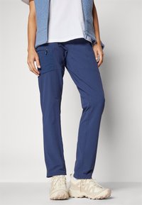 Navy outdoor pants in lightweight fabric featuring a side pocket, tapered design, and paired with light beige hiking shoes.