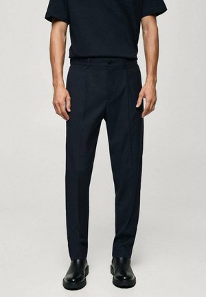 Pantaloni navy in una vestibilità tailored, con fondo piatto, due tasche laterali e una texture liscia, abbinati a stivali neri chunky.