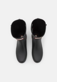 Botas de lluvia de goma negras con una textura lisa, diseño alto y punta redondeada. Presenta una pestaña para tirar y una etiqueta con el logo en la parte frontal.