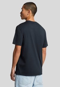 Camiseta de algodón negra con cuello redondo, mangas cortas y un ajuste relajado, que presenta una textura sencilla y suave.