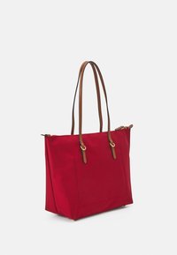 Czerwona płócienna torba na ramię z brązowymi skórzanymi ramiączkami, prostokątna forma, zamek błyskawiczny oraz płaska kieszeń z przodu. Wytrzymały materiał i czyste linie.
