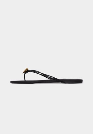 Černá plochá žabky s několika tenkými pásky a malou zlatou ozdobou ve tvaru kapky na předním pásku.