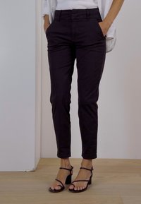 Musta räätälöity housu slim fit -mallilla, valmistettu sileästä kankaasta. Sisältää sivutaskut ja vyölenkit. Yhdistetty vierekkäisiin mustiin korkokenkiin.