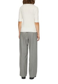 Witte kortekogige top met een ronde halslijn, gecombineerd met grijze high-waisted broek met een gestructureerd patroon en een relaxte pasvorm.