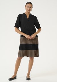 Schwarzes, plissiertes Kleid mit einem V-Ausschnitt, kurzen Puffärmeln und horizontalen Streifen in Schwarz und Braun, das knapp über dem Knie endet.