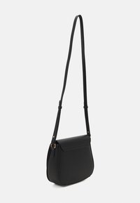 Borsa a tracolla in pelle nera con base curvata, tracolla regolabile, chiusura a patta magnetica e superficie liscia. Accessori in tonalità oro.