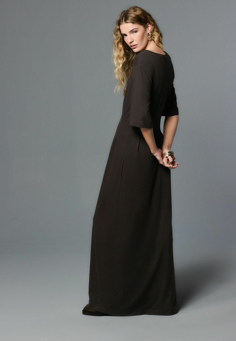 Tumepruuni kangaga maksikleit, lõdva istuvusega, laiad varrukad ja küljetlõiked, lihtsa disaini ja sileda tekstuuriga.