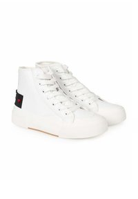 Białe wysokie trampki z gładką syntetyczną cholewką, płaską gumową podeszwą i czarną naszywką z tkaniny z czerwonym serduszkiem po boku.