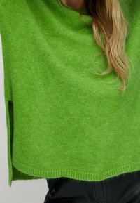 Grüner gestrickter Pullover aus weichem Stoff, mit lockerer Passform, seitlichen Schlitzen und einem runden Halsausschnitt mit gerippten Kanten.