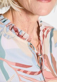 Florale Bluse mit Rüschkragen, weichem Stoff in Pastellfarben mit abstrakten Mustern und einer geknöpften Öffnung am Hals.