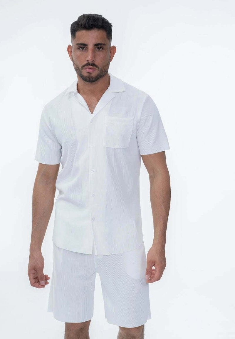 Chemise blanche à manches courtes avec un col et une poche, assortie à un short ; présente de légères rayures verticales et un tissu léger.