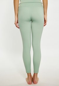 Vil�ágos zöld leggings rugalmas anyagból, alakra szabott dizájn, magas derék, és varrás nélküli kivitel, látható minták vagy díszítések nélkül.