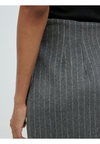 Jupe en mélange de laine gris avec des rayures verticales. La texture est douce avec une finition légèrement duveteuse, vue de dos avec un bras visible.