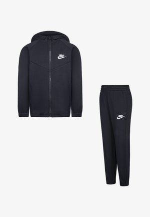 Jūras spēku treniņu komplekts, kas ietver zip-up kapuci ar auklas kapuci un atbilstošas elastīgas jostas bikses, abos ir iekļauti balti Nike logotipa akcenti.