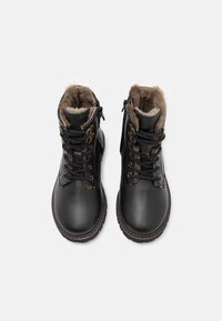 Botas de cuero negro con forro de piel sintética. Cuentan con cierre de cordones, cremallera lateral y punta redonda. Suela de goma con patrón de tracción texturizado.