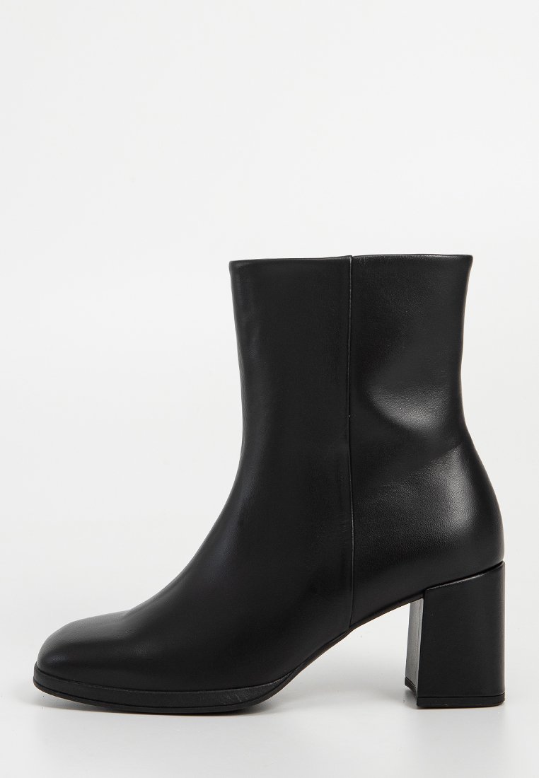Fekete bőr bokacsizma lekerekített orral, sima felülettel és 7,5 cm-es tömbsarokkal. Karcsú, letisztult dizájn, oldalsó cipzárral.