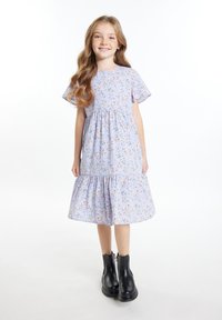 Hellblaumann blumiges Kleid mit kurzen Rüschärmel, gestuftem Rock und rundem Halsausschnitt, kombiniert mit schwarzen Knöchelstiefeln.