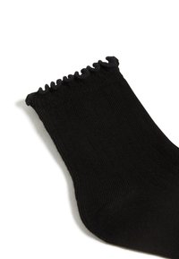 Schwarze gerippte Socke mit einem gerafften oberen Rand, verfügt über eine glatte Textur und eine standardmäßige Form. Es sind keine auffälligen Muster oder Hardware vorhanden.