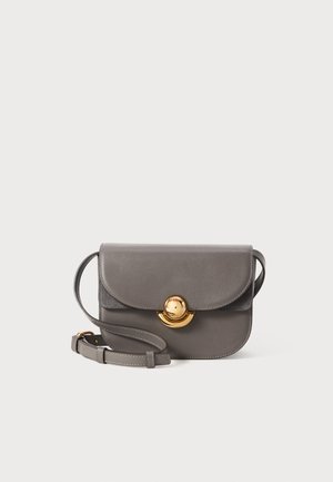 Grey leather crossbody bag with a rounded flap, gold circular hardware, and an adjustable strap. Smooth texture with a sleek design.