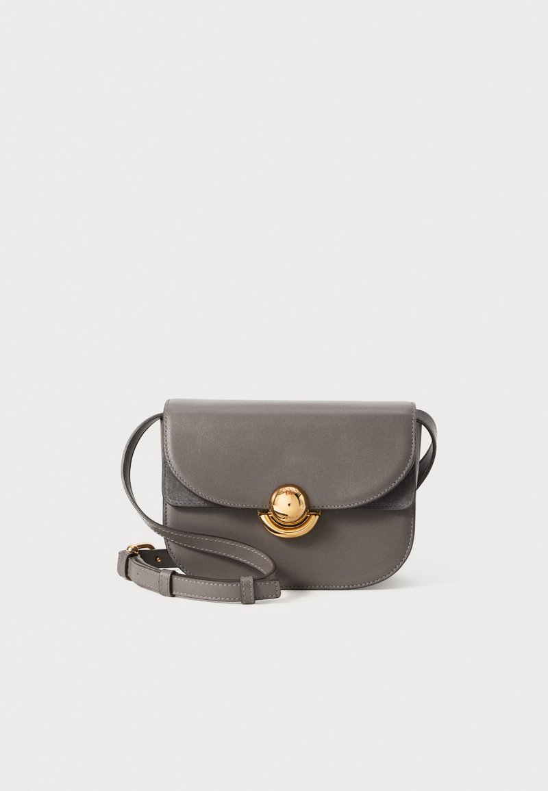 Šedá kožená crossbody kabelka s kulatým klopou, zlatými kruhovými kovovými prvky a nastavitelným popruhem. Hladká textura s elegantním designem.